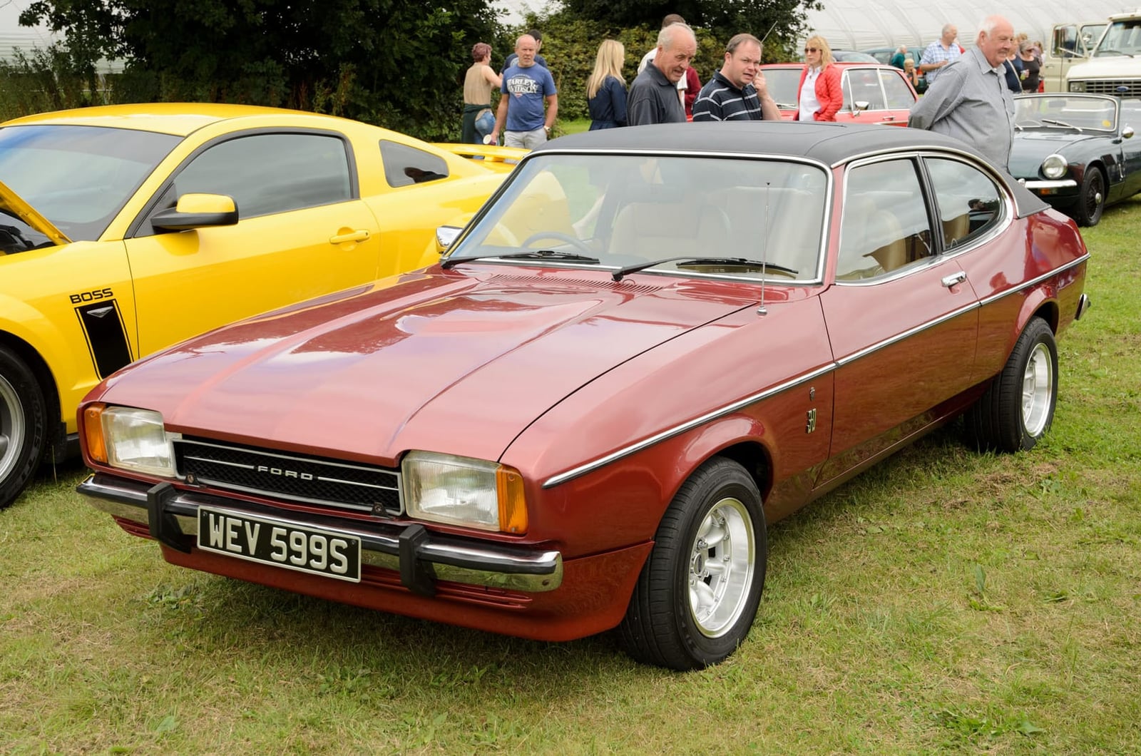 A maroon 1977 Ford Capri Mk2 3.0 Ghia with a UK registration on a show field