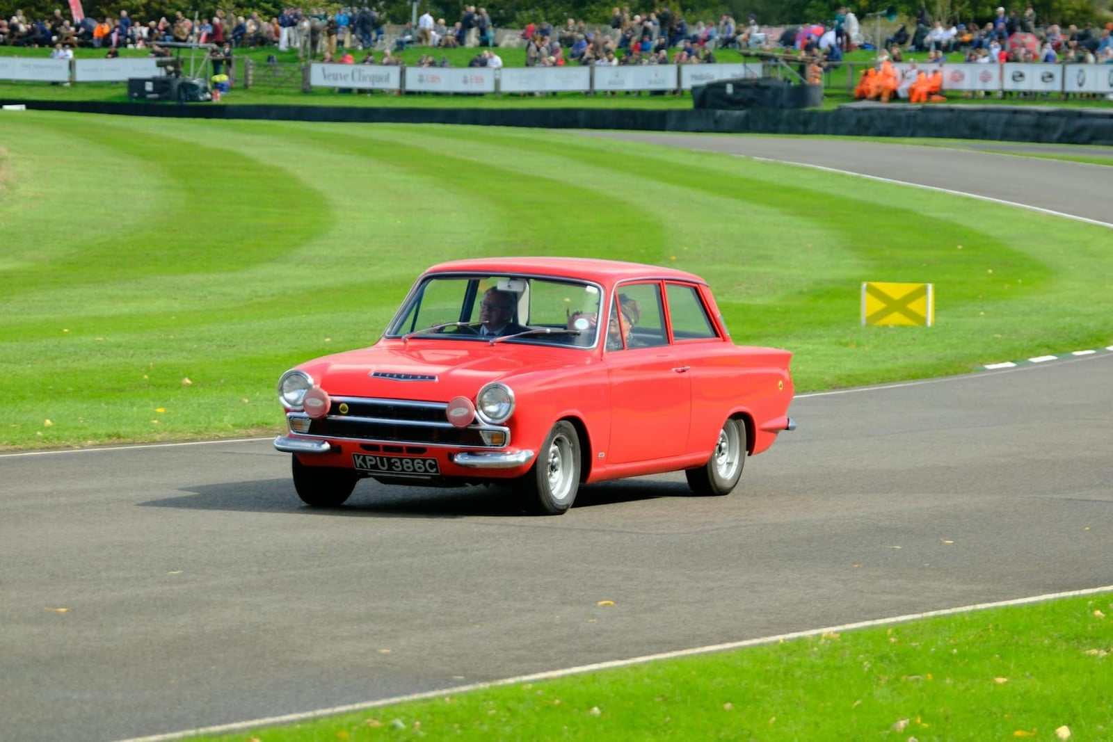A red Ford Cortina Mk1 cornering on a race circuit