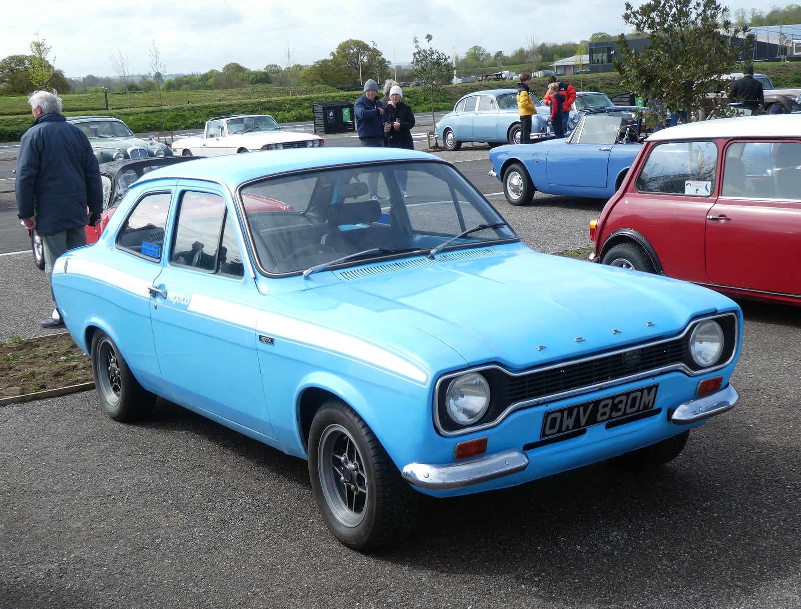 A light blue Mk1 Ford Escort Mexico at a show, front three-quarter view