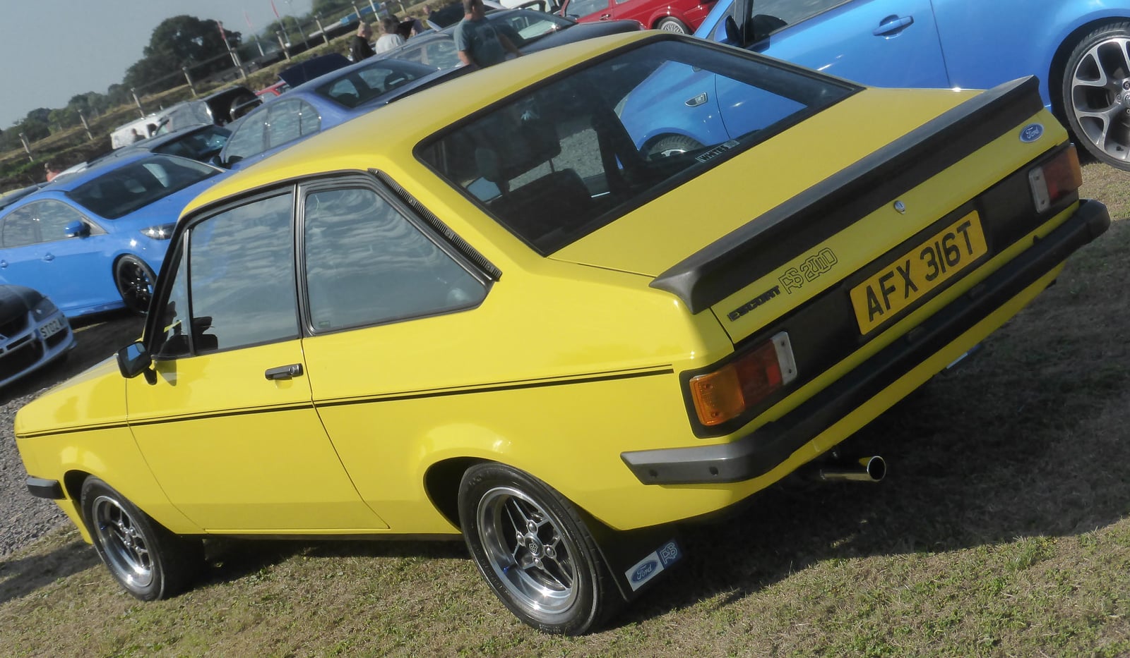 A yellow Mk2 Ford Escort RS2000 at a show, front three-quarter view