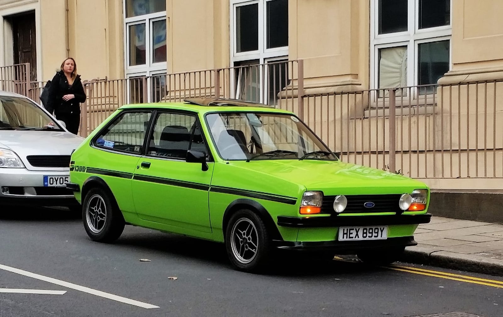 A bright green Ford Fiesta Mk1 parked on a street outside a terrace, side view, UK registration HEX 699Y