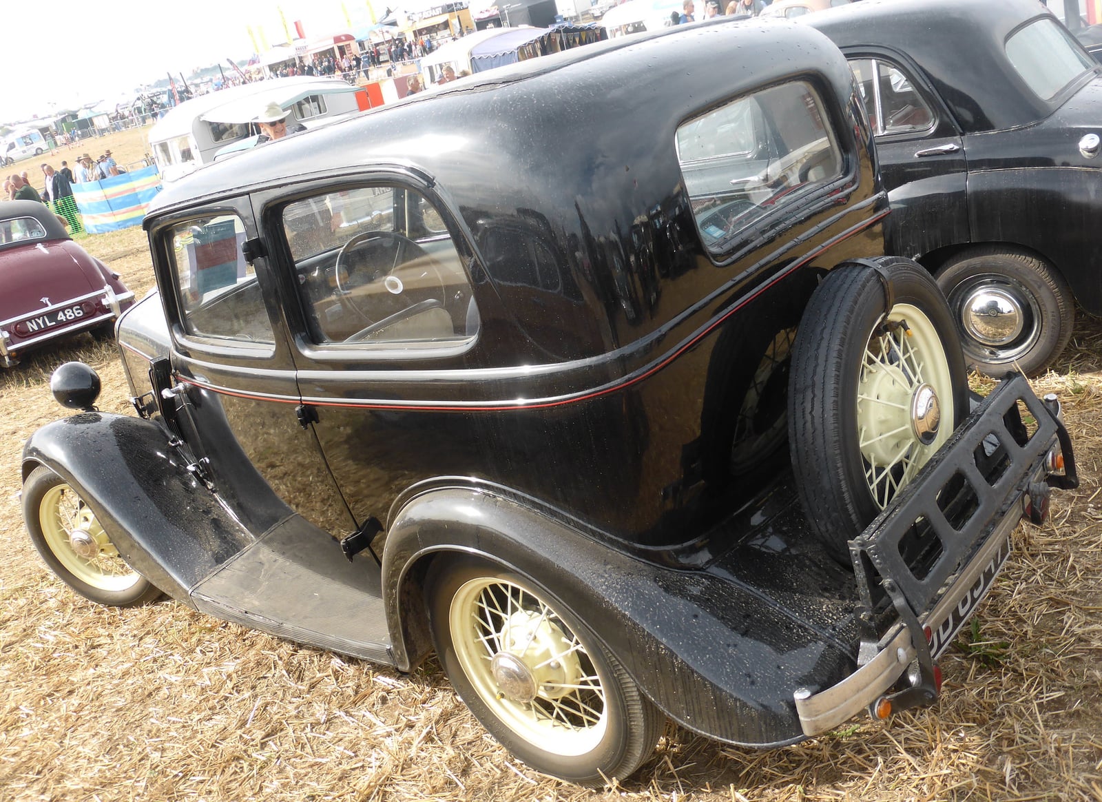 A black Ford Model Y saloon at a show, rear three-quarter view