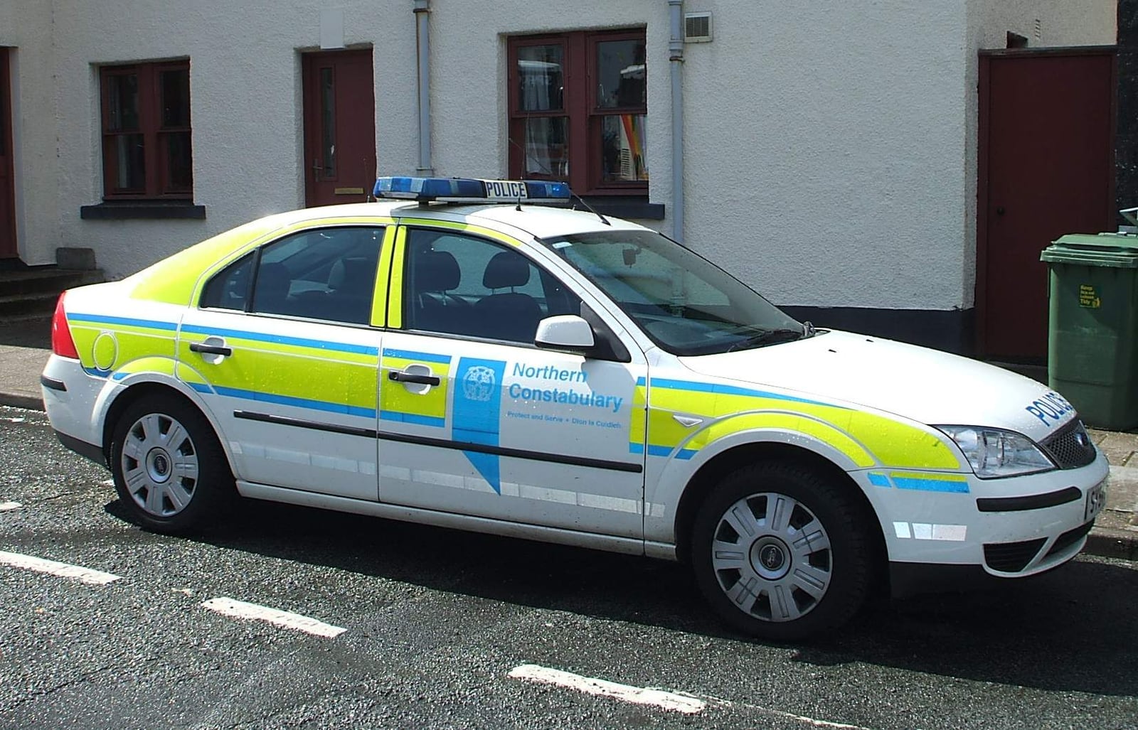 A Mk3 Ford Mondeo saloon in British police livery parked outside a row of houses