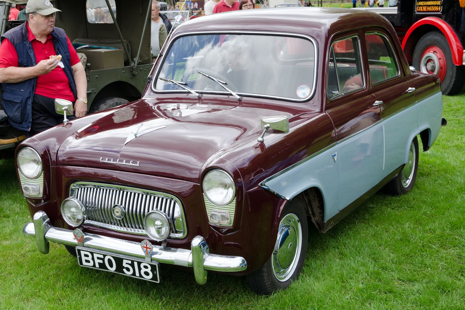 A maroon Ford Prefect 100E saloon at a show, front three-quarter view