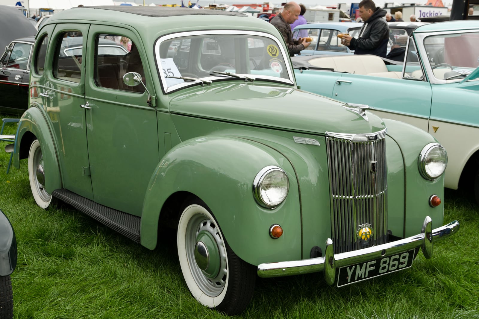 A green upright Ford Prefect E493A saloon at a show, front three-quarter view