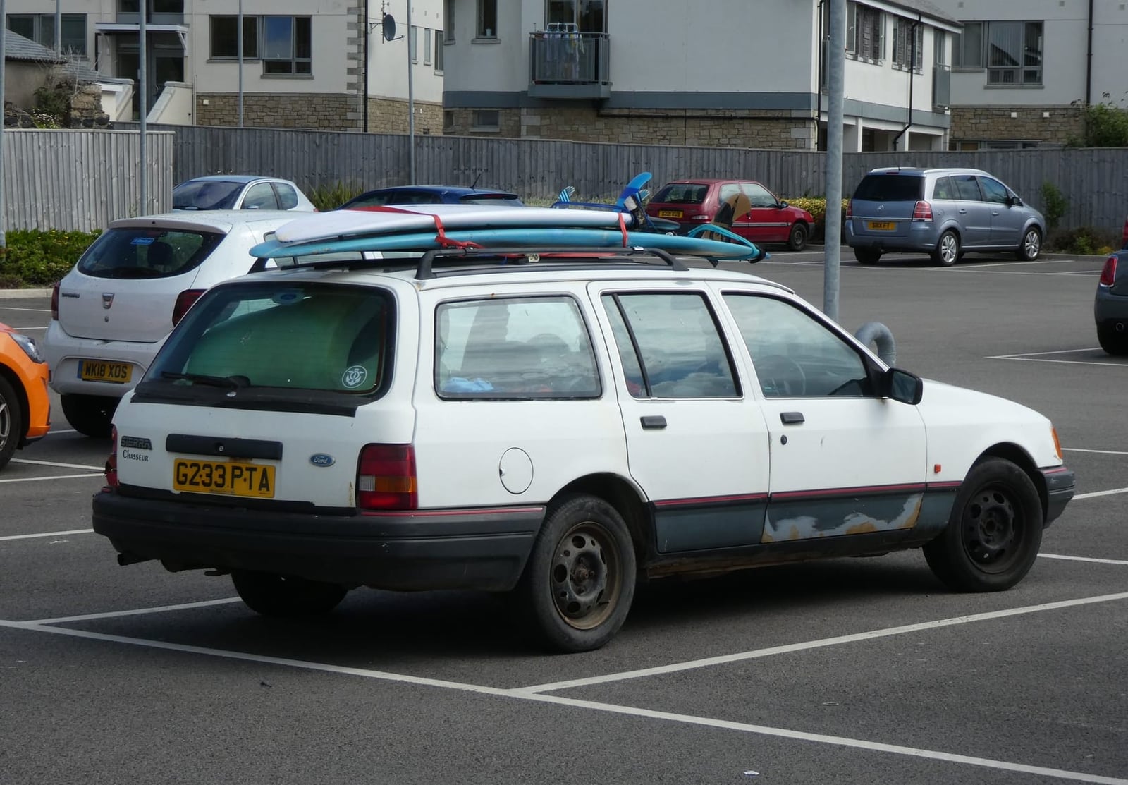 A white 1989 Ford Sierra Chasseur 2.0 estate in a car park, rear three-quarter view, UK registration G233 PTA