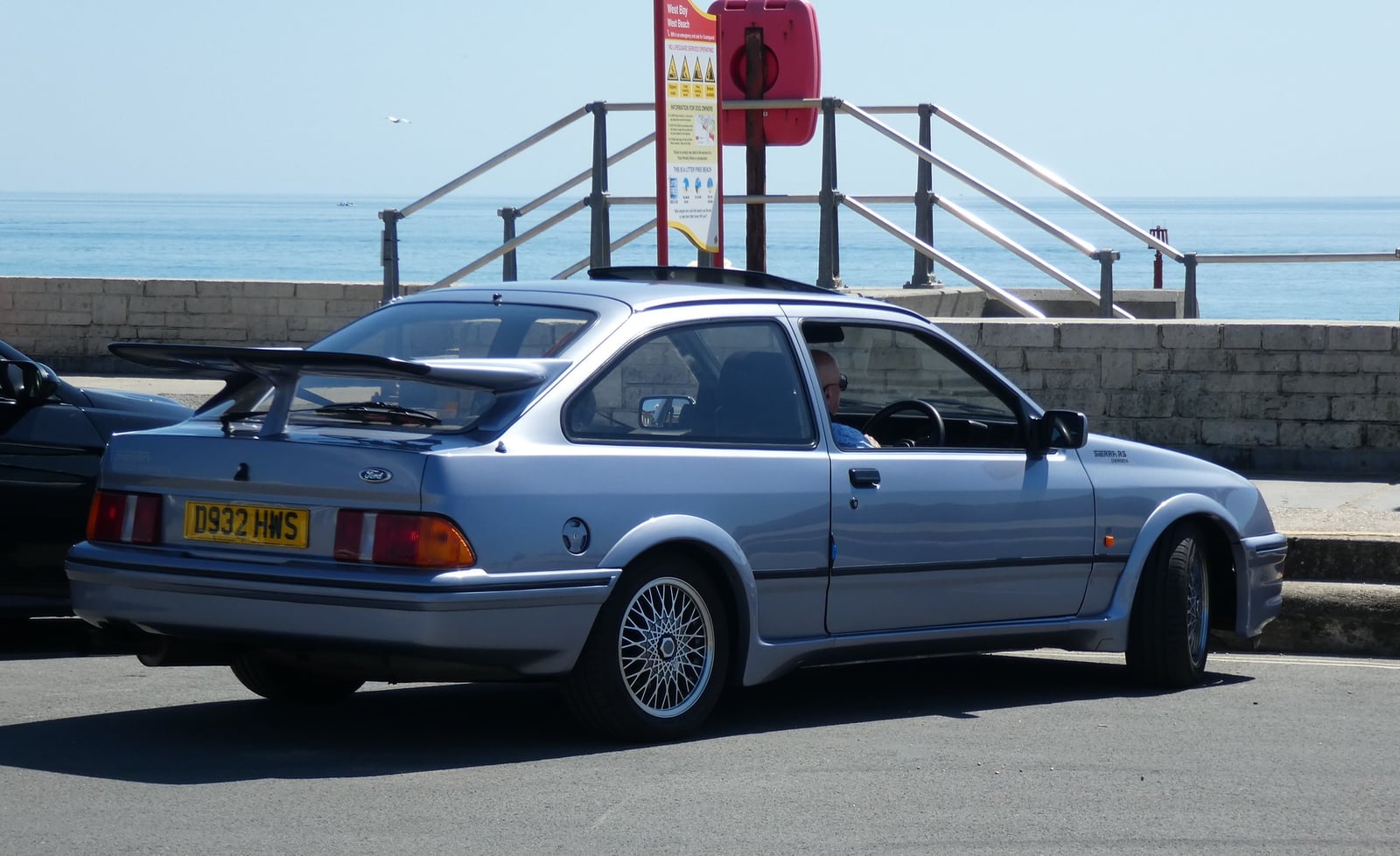 A white four-door Ford Sierra Sapphire RS Cosworth by the coast