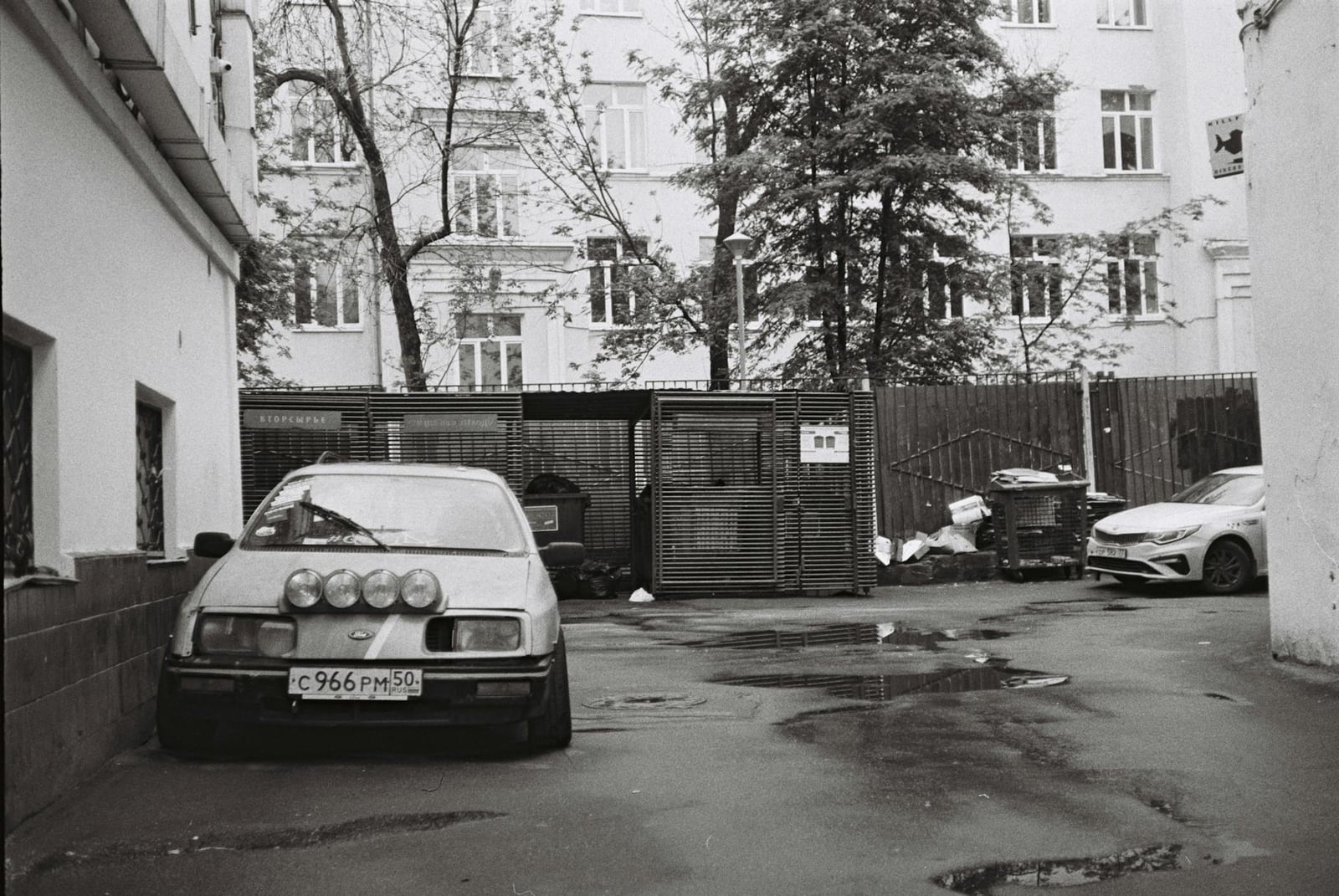 A black-and-white photograph of a Ford Sierra with driving lamps in a courtyard