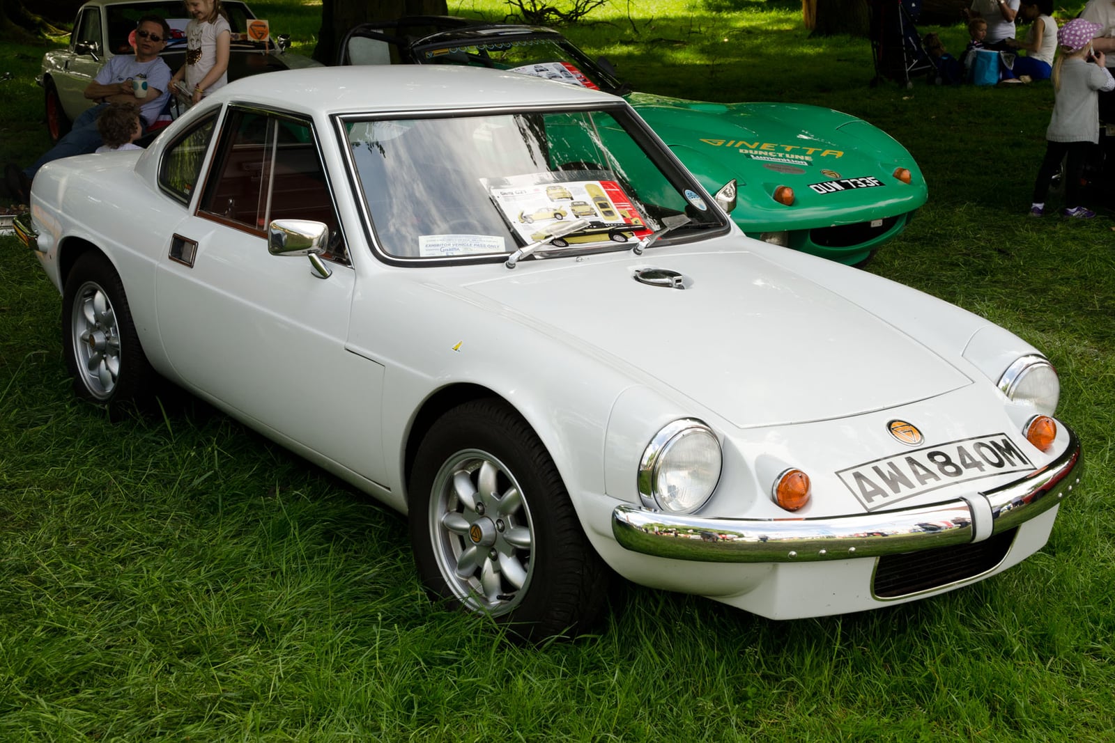 A white Ginetta G15 coupe, front three-quarter view on grass at a classic car show