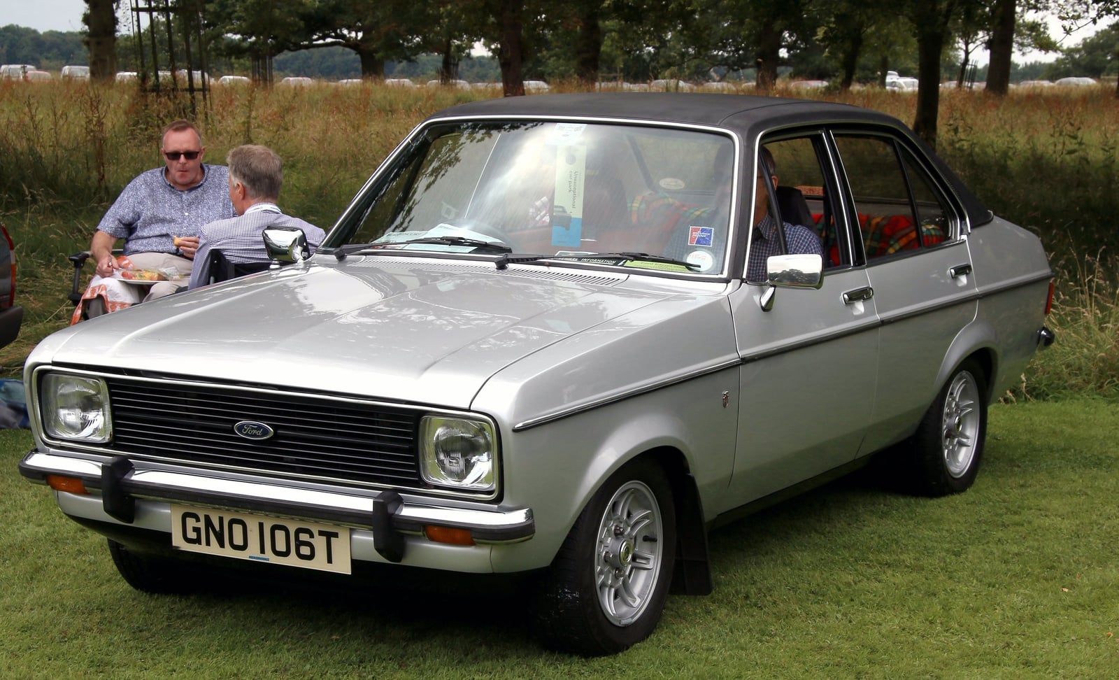 A silver Ford Escort Mk2 Ghia four-door saloon at a show, front three-quarter view