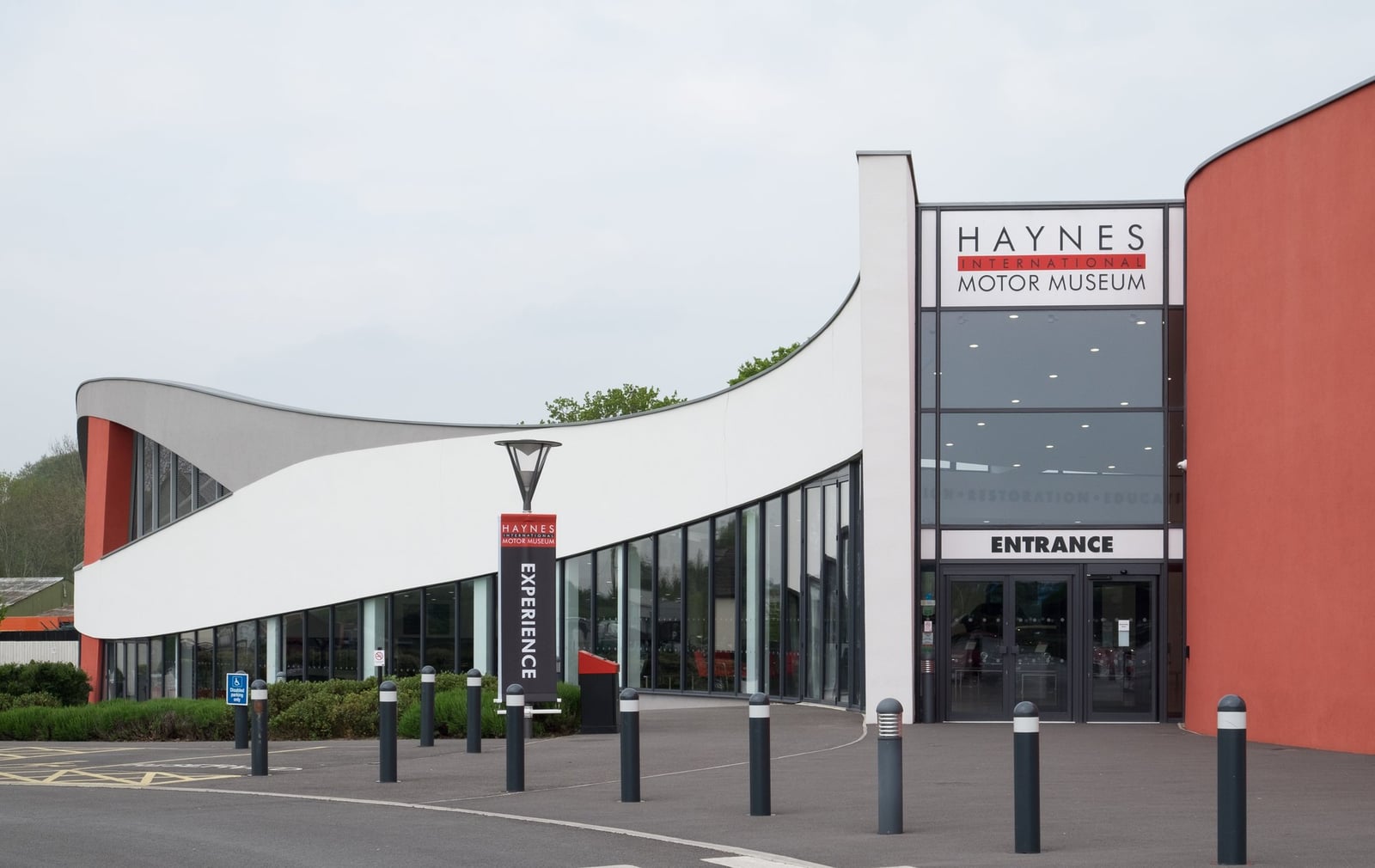 The curved white and orange entrance building of the Haynes International Motor Museum at Sparkford, Somerset