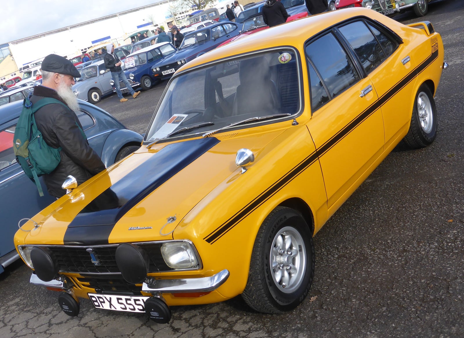 A Sundance Yellow Hillman Avenger Tiger (1971) with matt-black bonnet stripe and auxiliary driving lamps, front three-quarter view outdoors