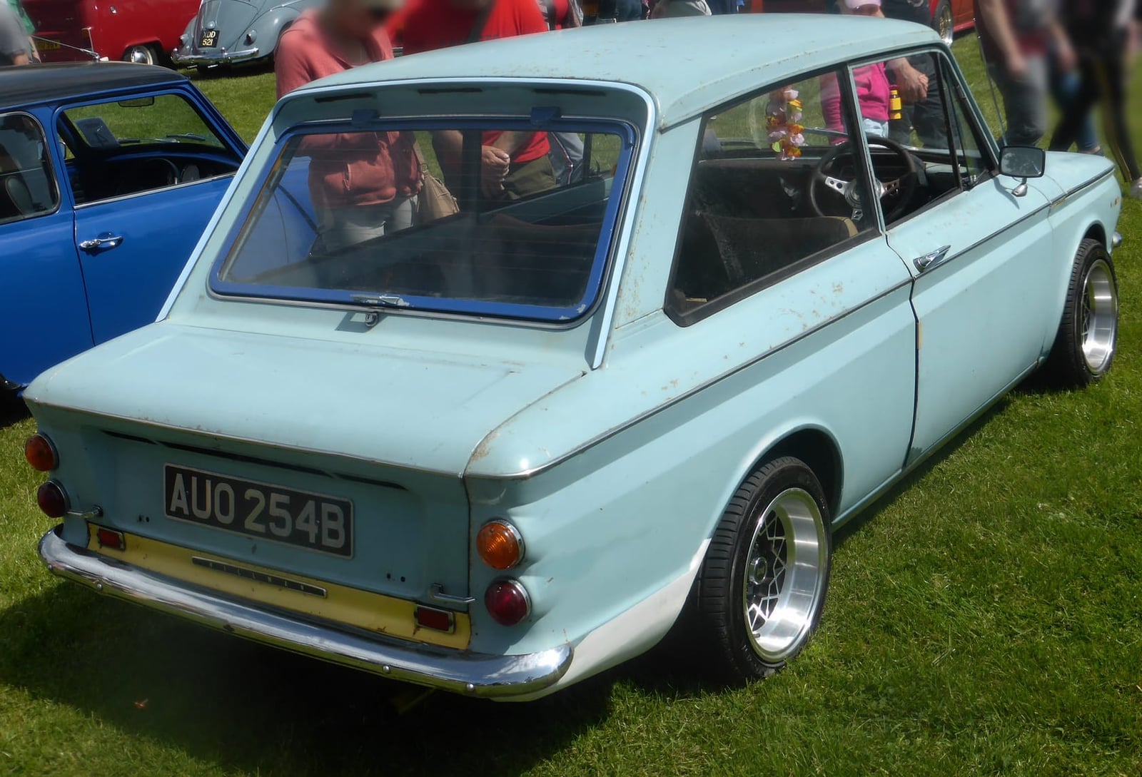 The rear of a light blue 1964 Hillman Imp, UK registration AUO 254B, showing the engine cover and large rear window