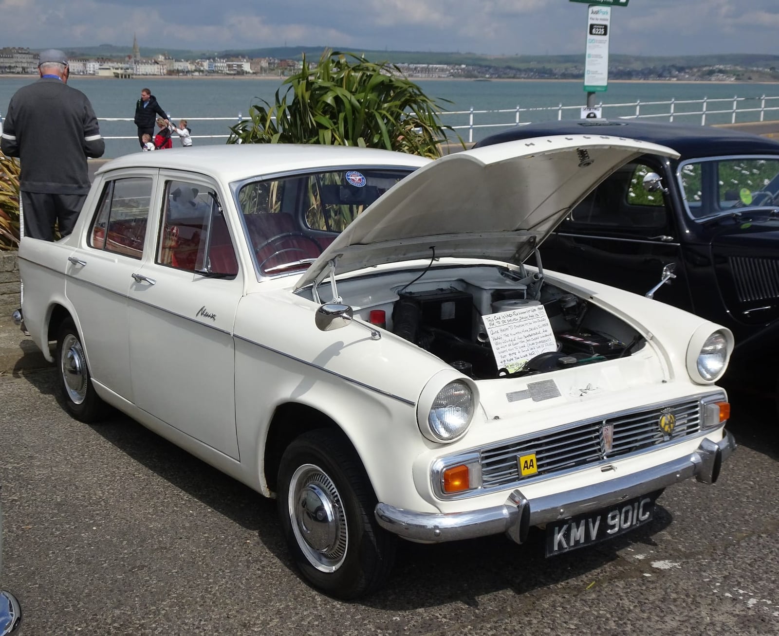 A white Hillman Minx Series VI with its bonnet raised at a classic car show