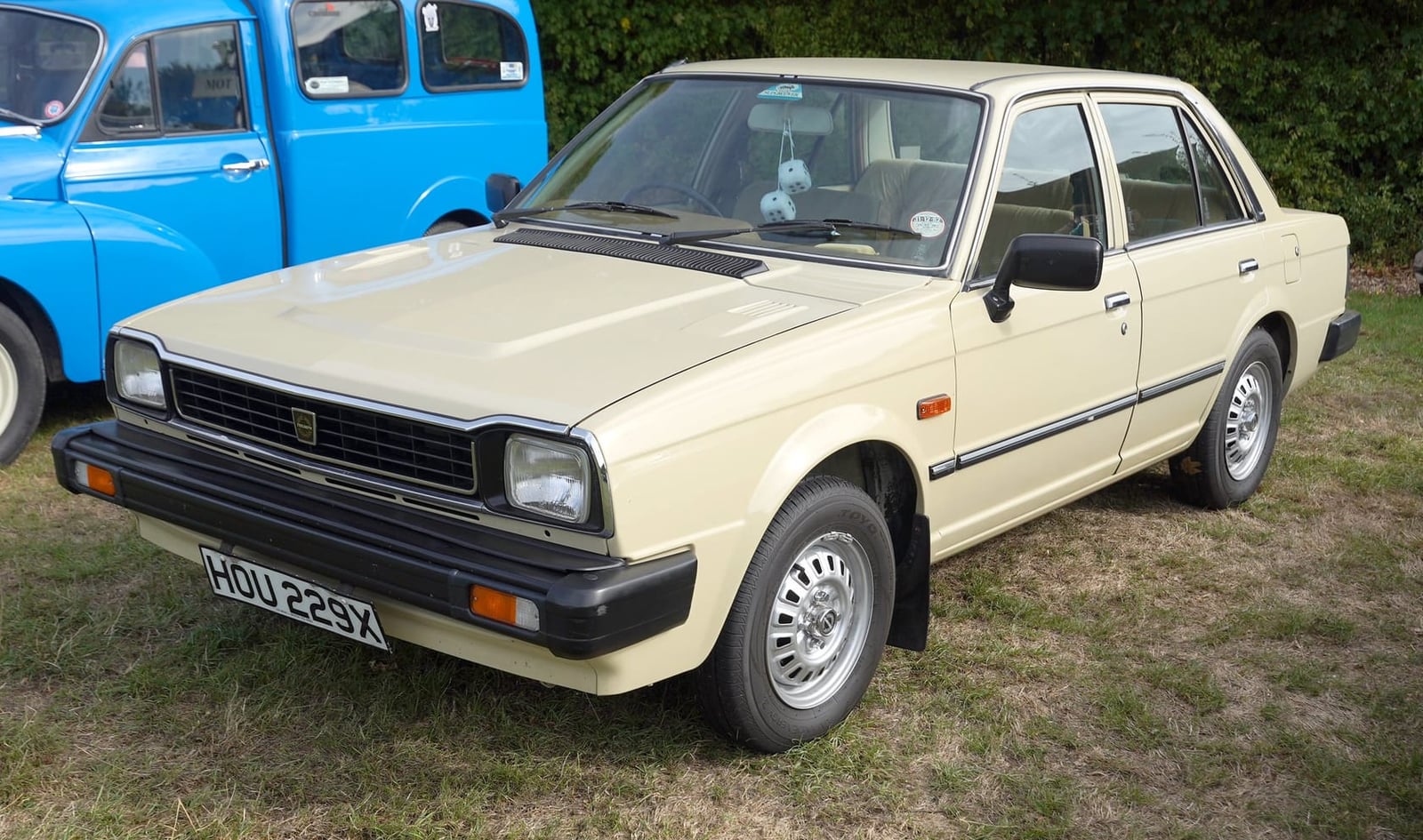 A cream Triumph Acclaim on grass at a classic vehicle show, front three-quarter view, UK registration HOU 229X