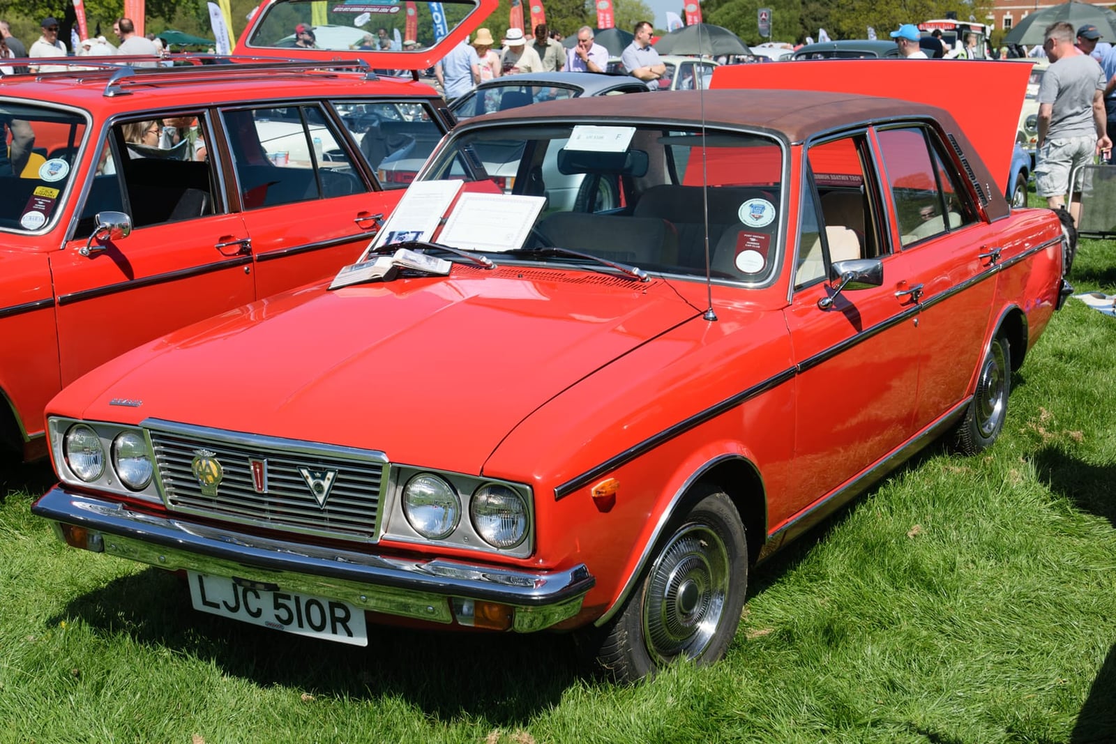 A red Humber Sceptre Mk III with vinyl roof at a busy classic show, front three-quarter view, UK registration LJC 510R