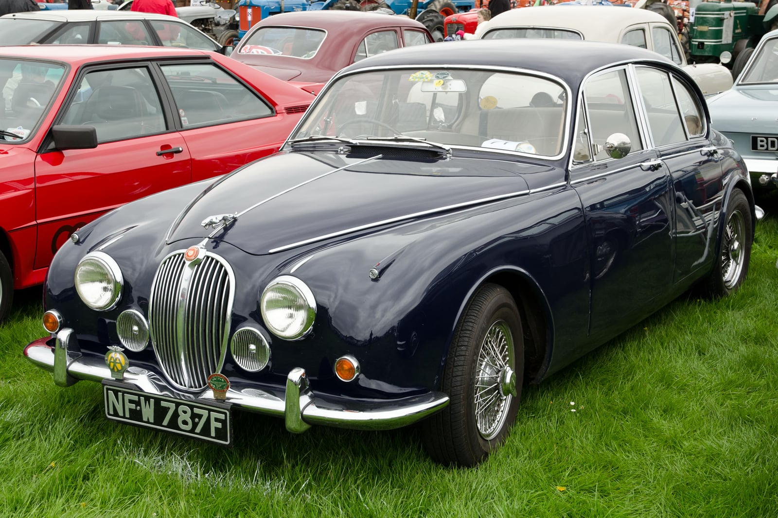 A dark blue Jaguar 340 saloon with slim bumpers and wire wheels, front three-quarter view