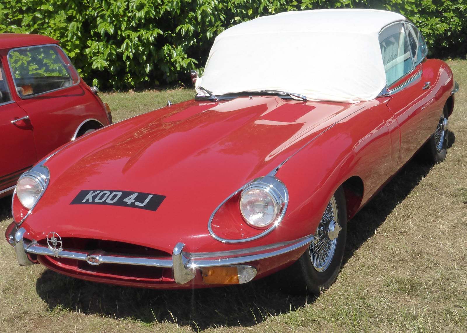 A red Jaguar E-Type Series 2 2+2 with a white hardtop, front three-quarter view