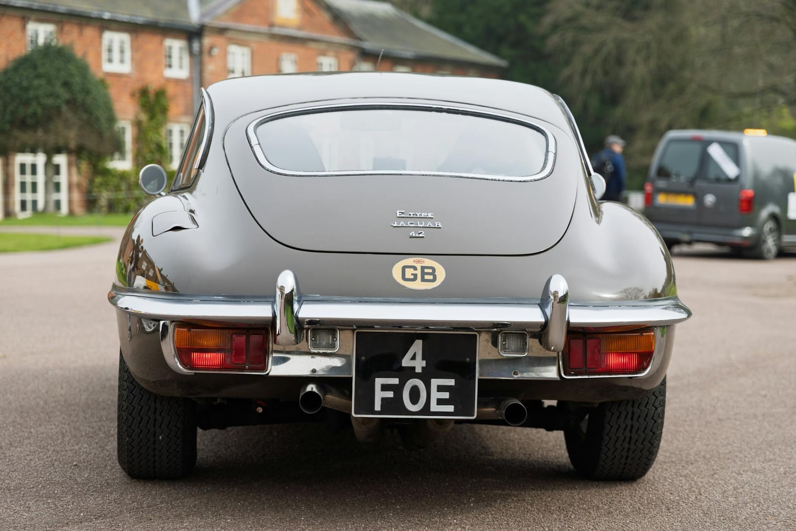Rear of a grey Jaguar E-Type fixed-head coupe showing the "E-TYPE JAGUAR 4.2" bootlid badge
