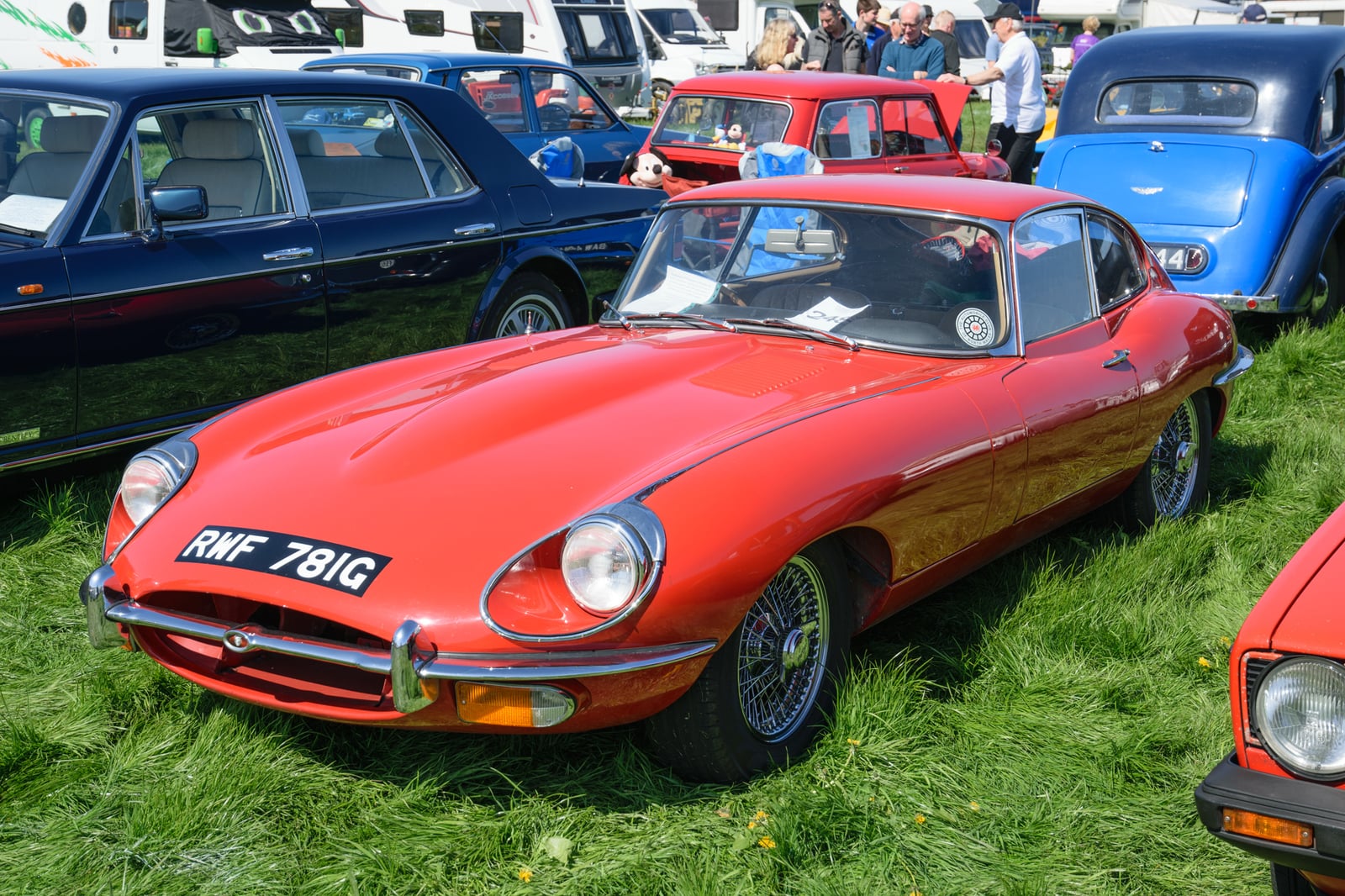 A red Jaguar E-Type Series 2 fixed-head coupe with open headlamps and wire wheels, front three-quarter view