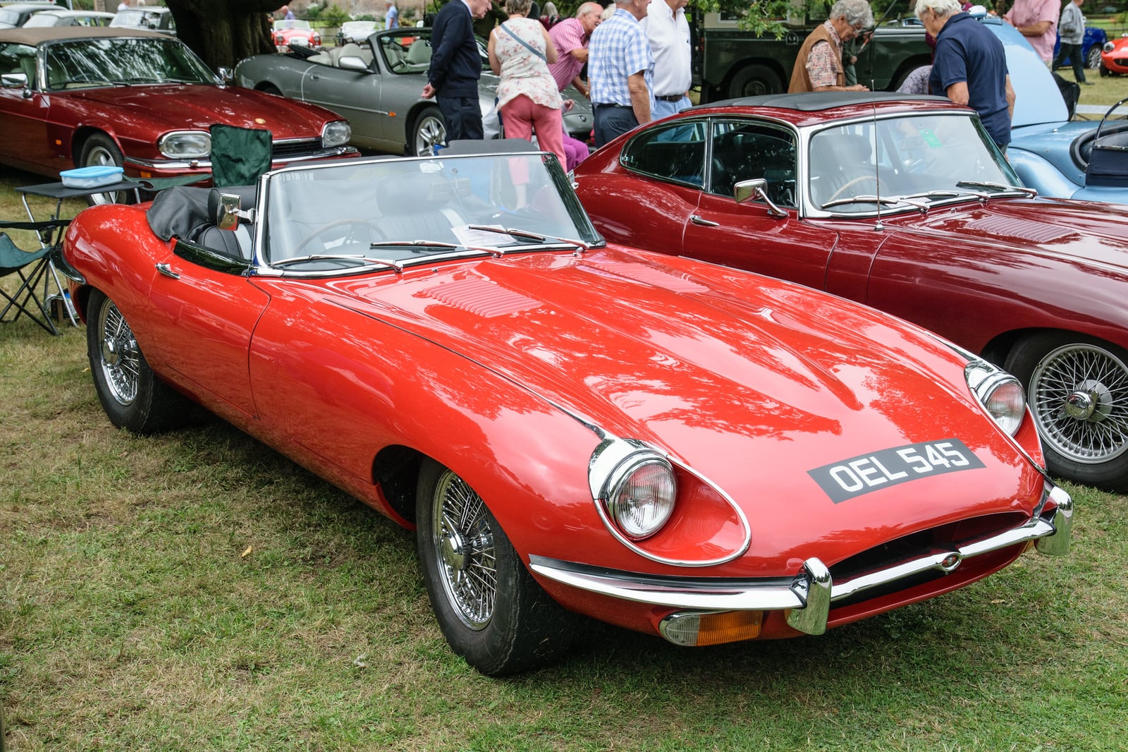 A red Jaguar E-Type Series 2 roadster parked at a classic car show