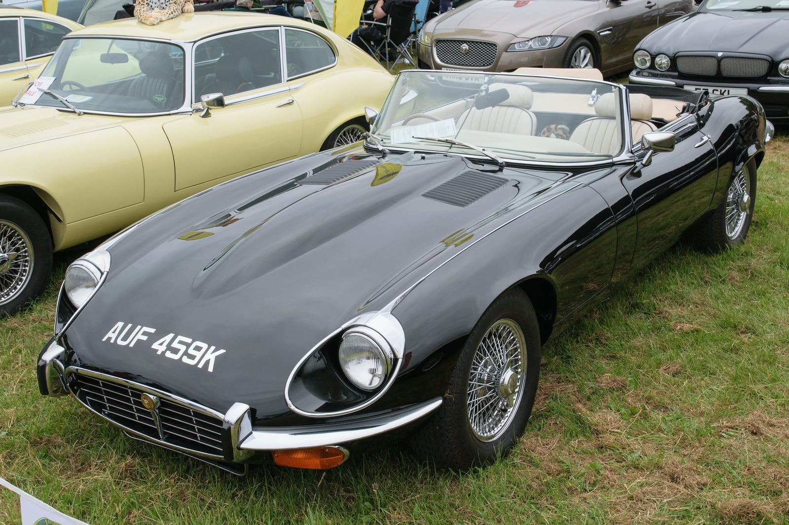 A red Jaguar E-Type Series 3 V12 roadster with a black hardtop at a show, front three-quarter view