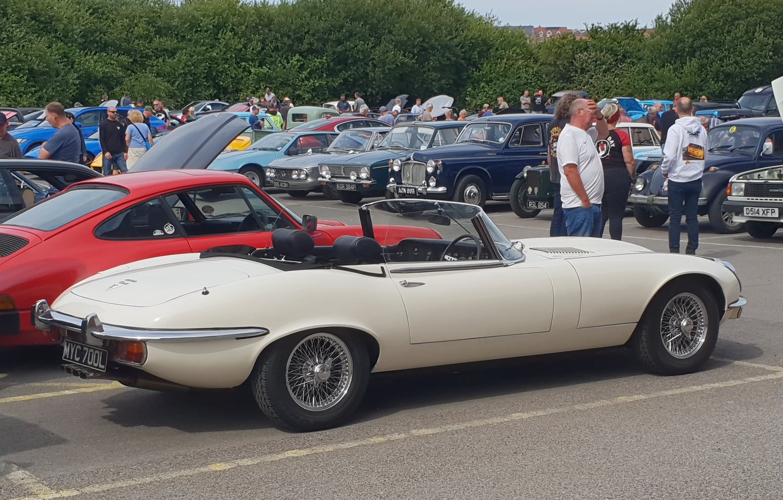 A silver Jaguar E-Type Series 3 V12 roadster with the hood down, parked on grass