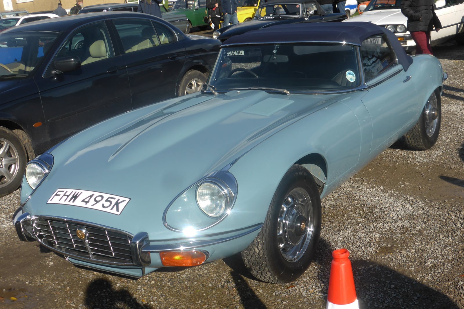A light blue Jaguar E-Type Series 3 V12 roadster with the hood up, front three-quarter view