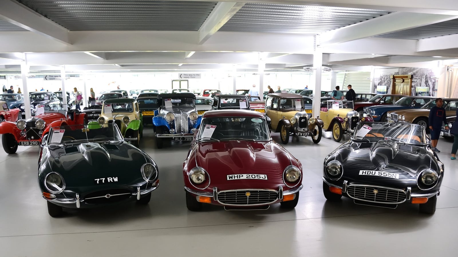 A line of Jaguar E-Types, from an early roadster to a late V12, on display in a hall at the British Motor Museum, Gaydon