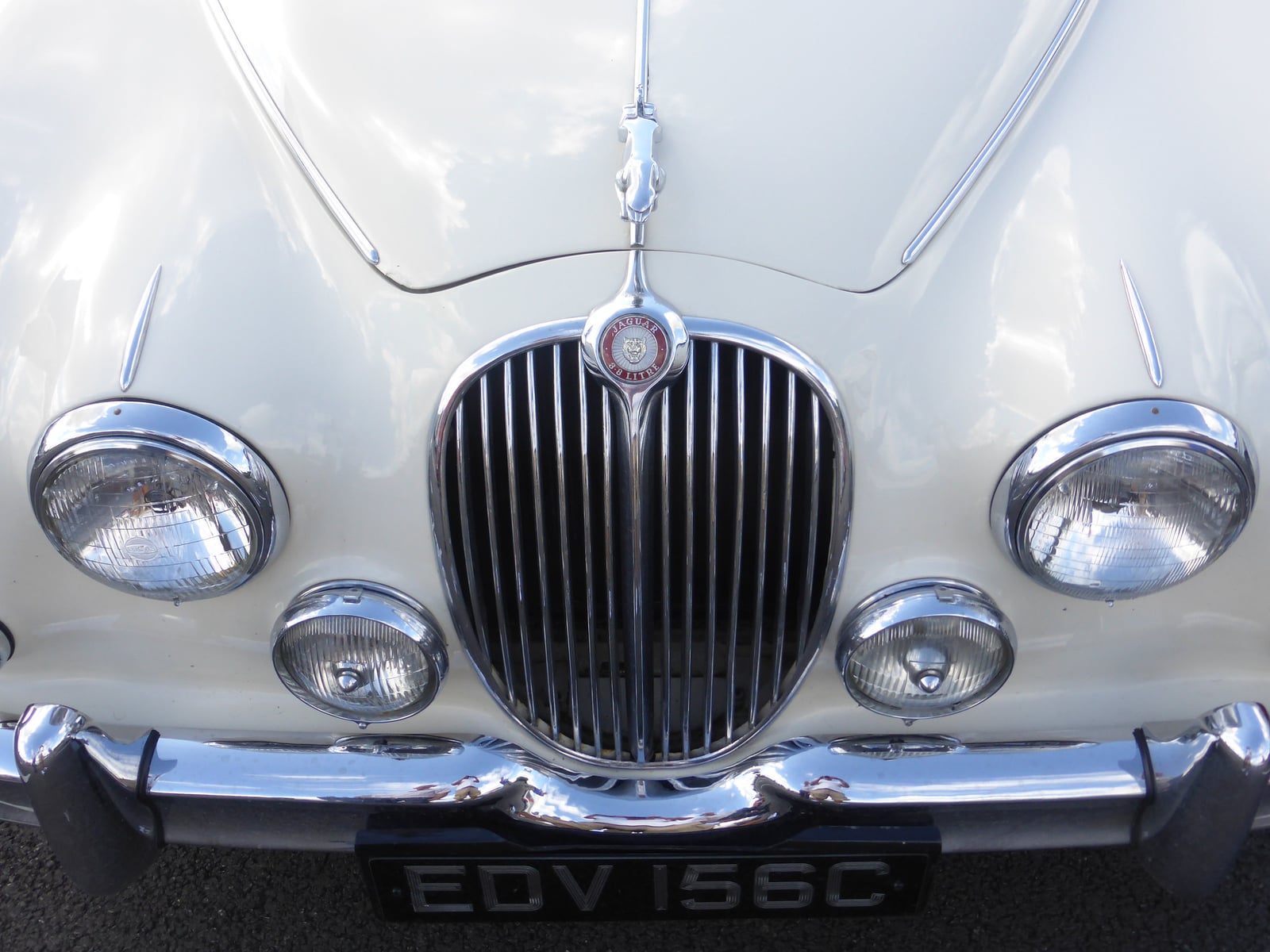 Close-up of the chrome grille, headlamps and fog lamps of a cream Jaguar Mk2