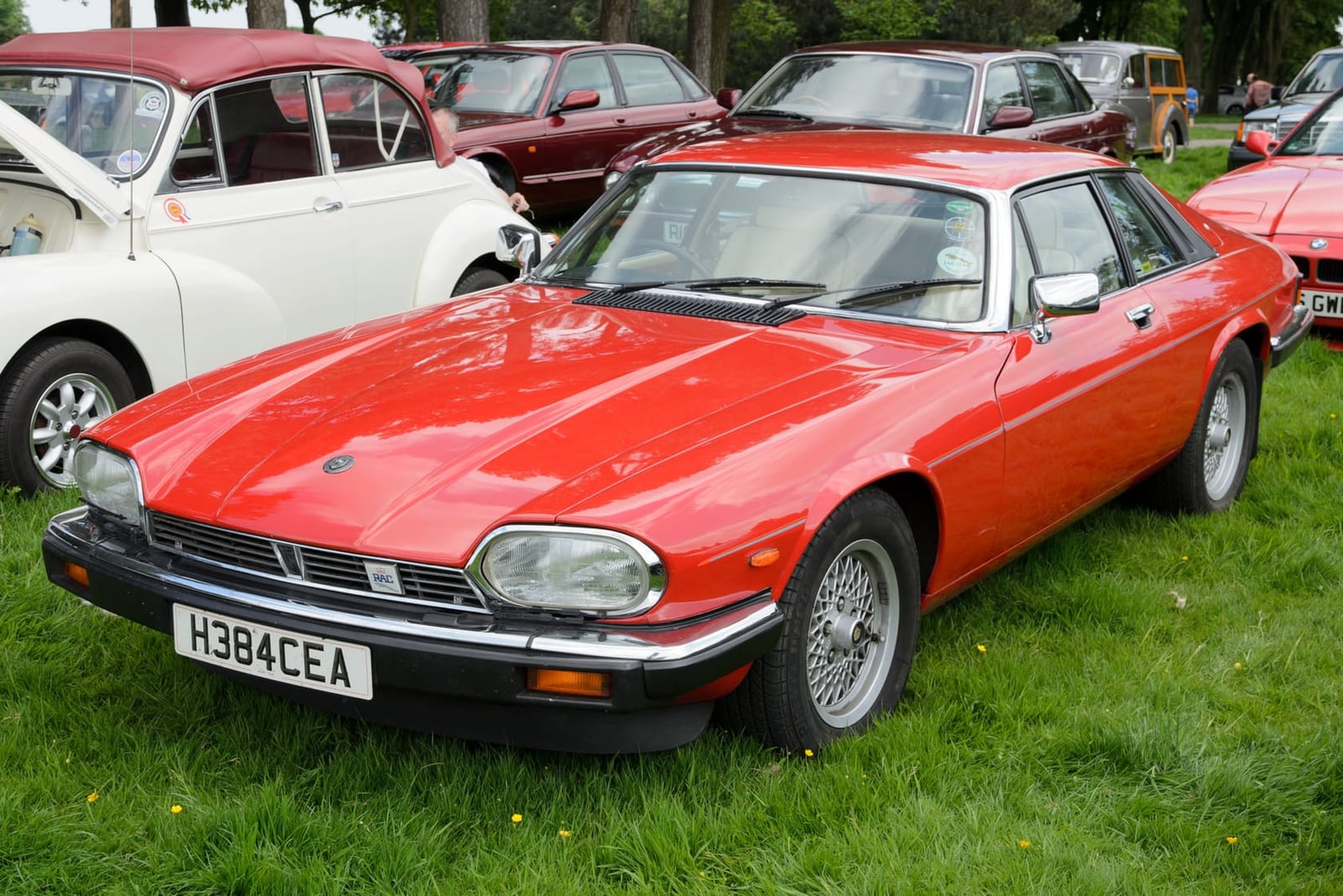 A red 1990 Jaguar XJ-S 3.6 coupé with a UK registration parked on grass at a classic car show