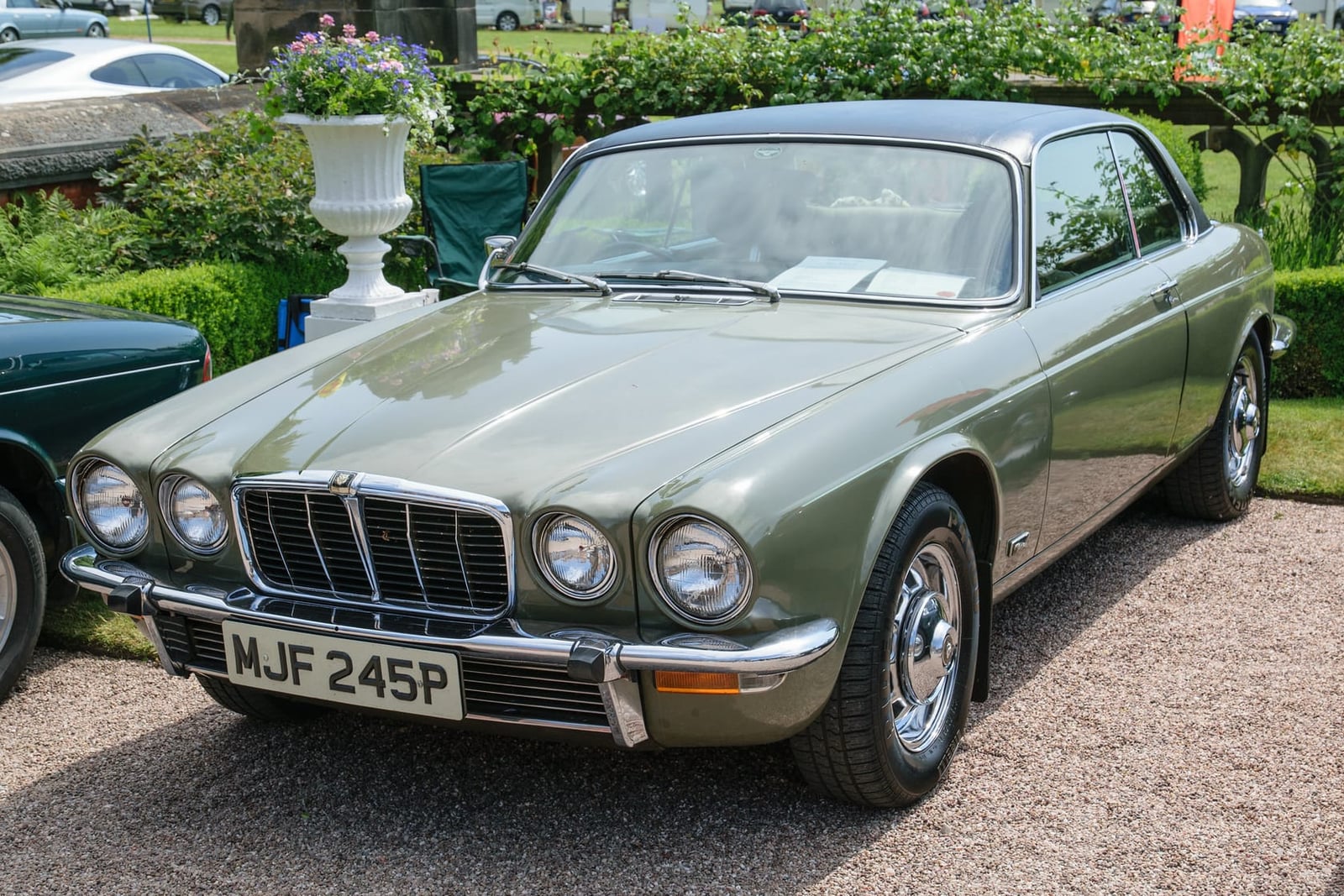 A sage green 1976 Jaguar XJ6 Series 2 4.2 with a UK registration parked on gravel at a show