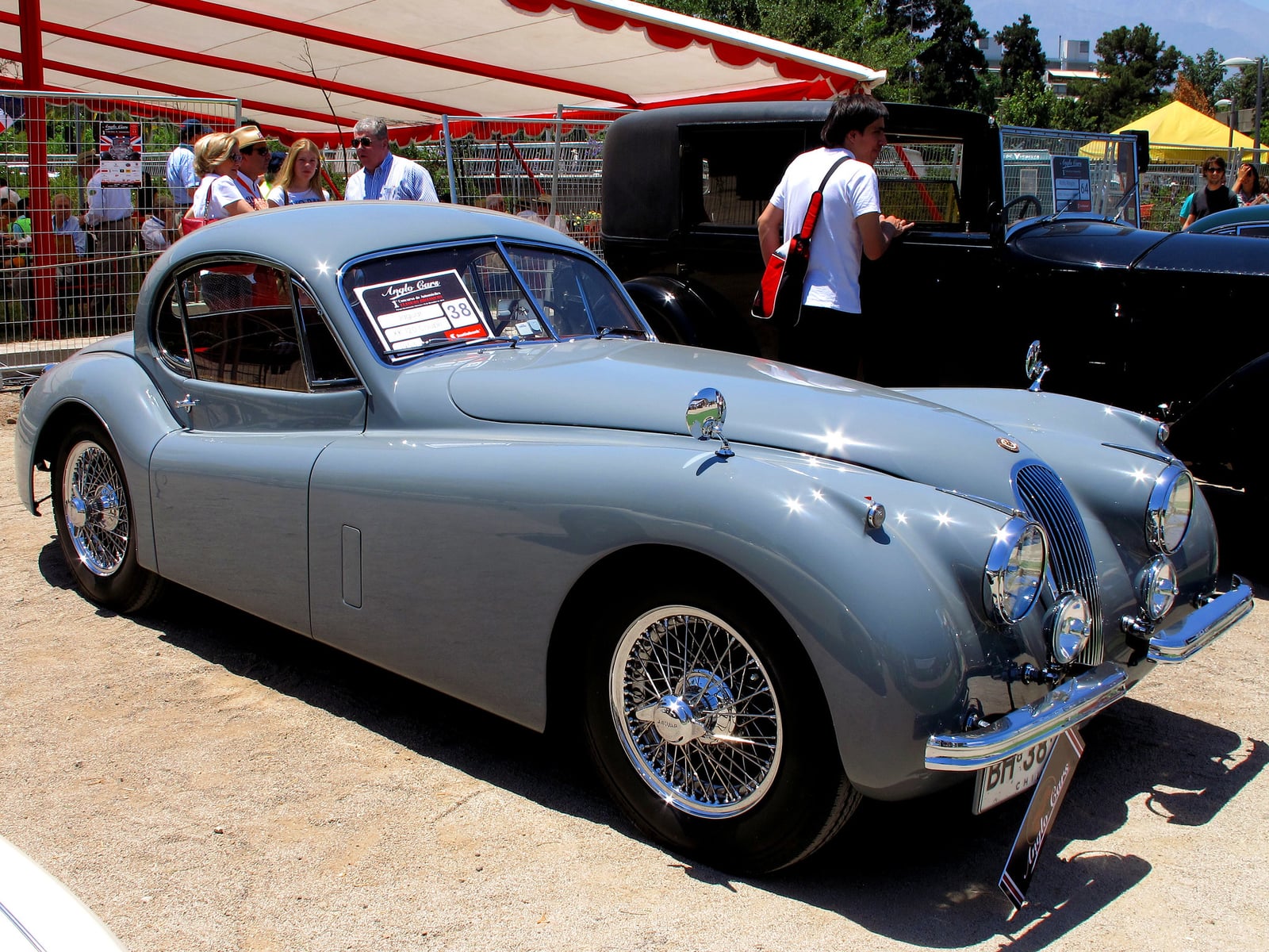 A pale blue Jaguar XK120 fixed-head coupe with wire wheels at a show, front three-quarter view