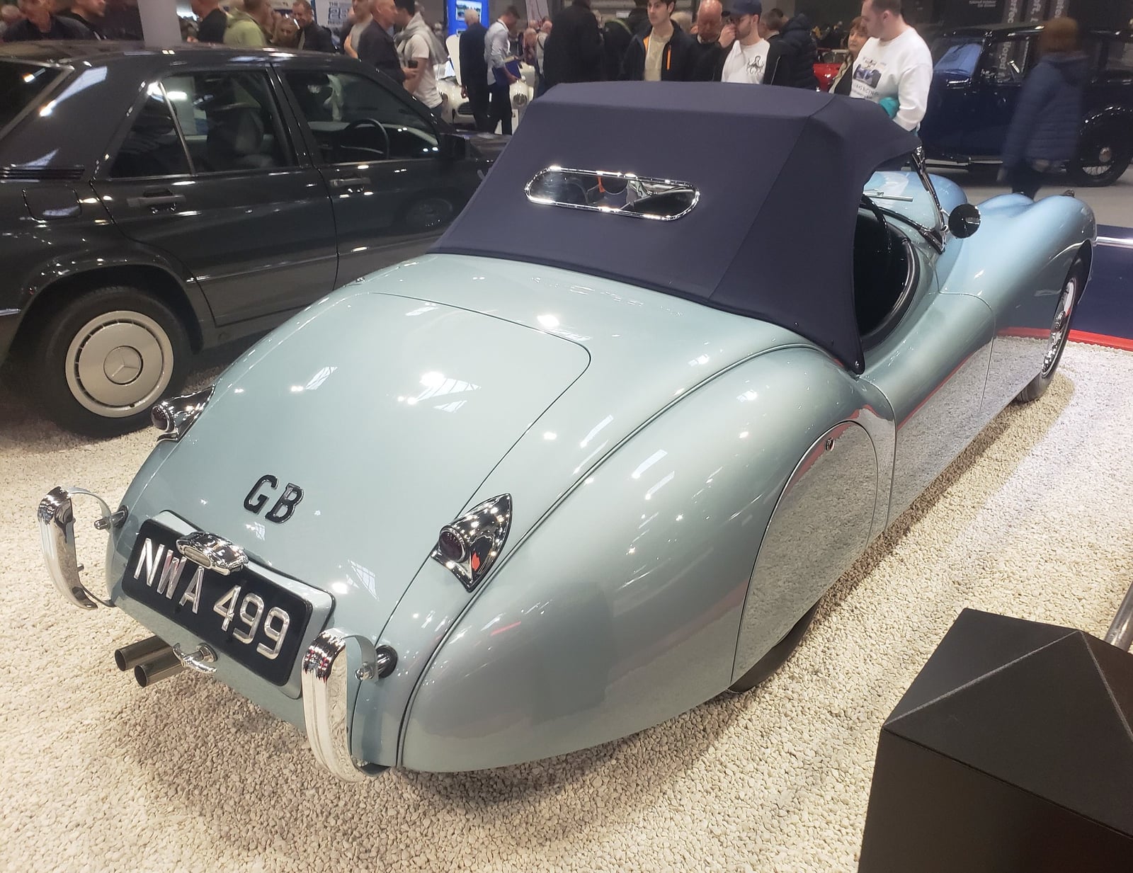 A pale green Jaguar XK120 drophead coupe seen from the rear three-quarter, hood up, UK registration NWA 499