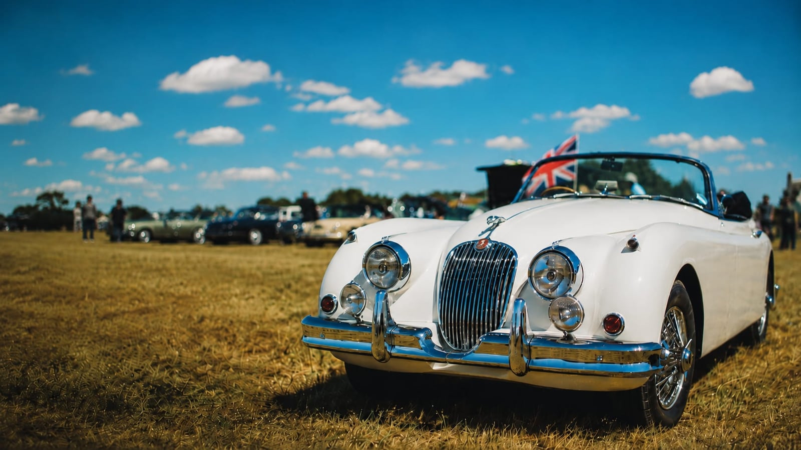 A white Jaguar XK150 drophead at a summer show, front view