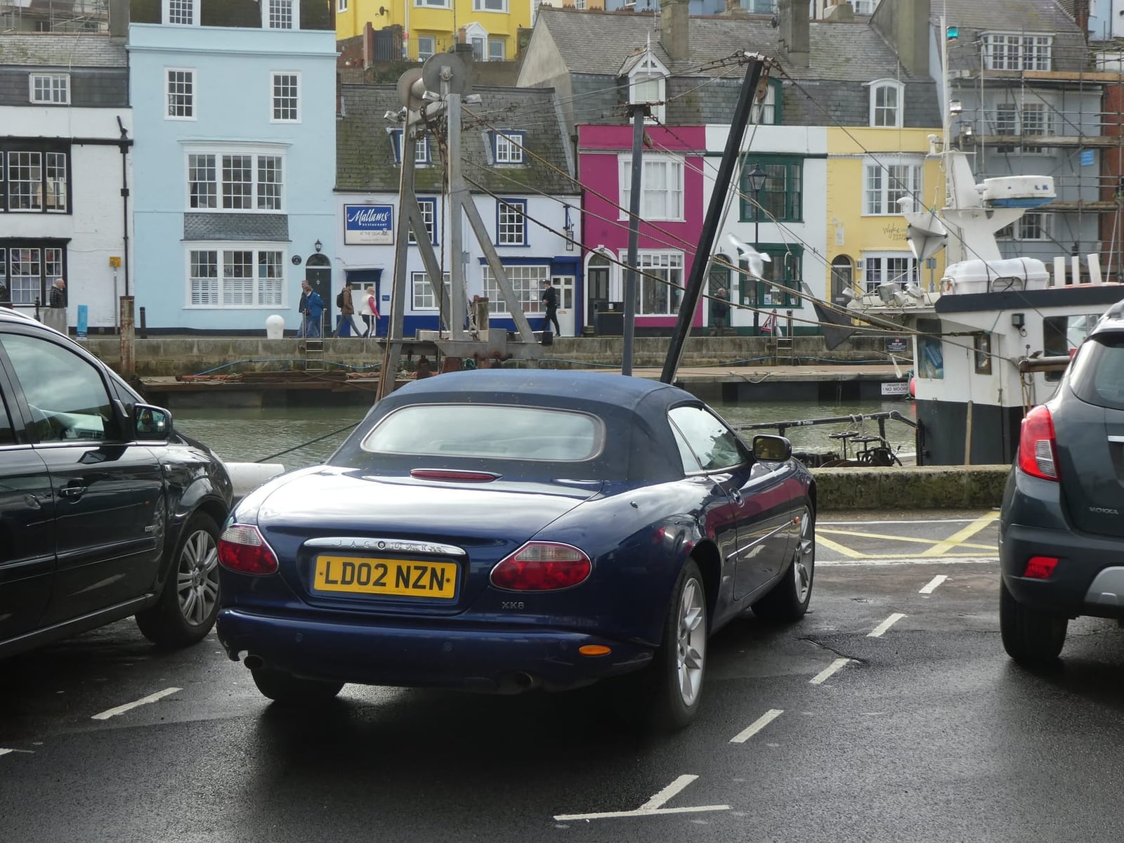 A blue Jaguar XK8 convertible with UK registration LD02 NZW in a harbour town