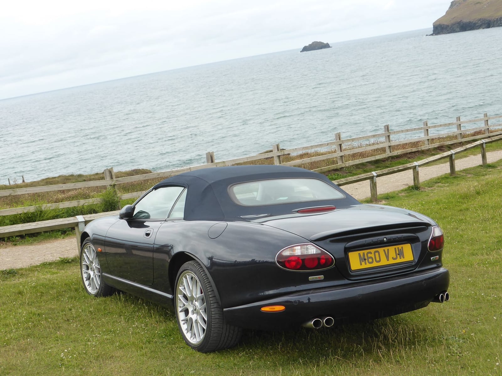 A black 2006 Jaguar XKR 4.2S convertible with UK registration H60 VJW by the coast