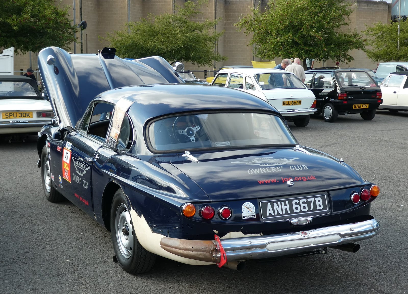 A dark blue Jensen CV8 with its bonnet open, showing the Chrysler V8 engine