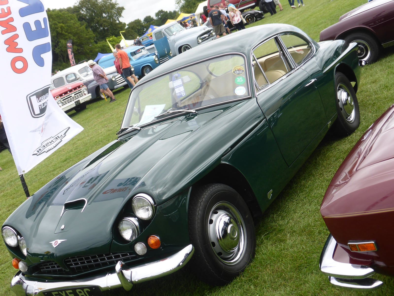A dark green Jensen CV8 Mk III on grass, front three-quarter view