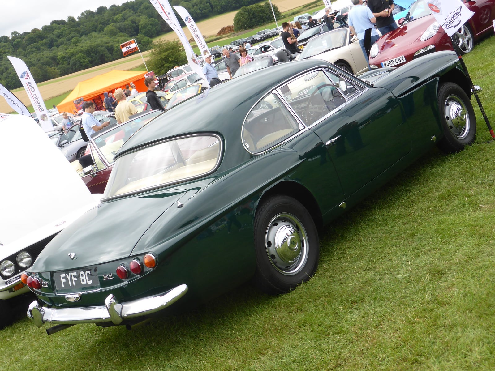 A dark green Jensen CV8 Mk III seen from the side and rear