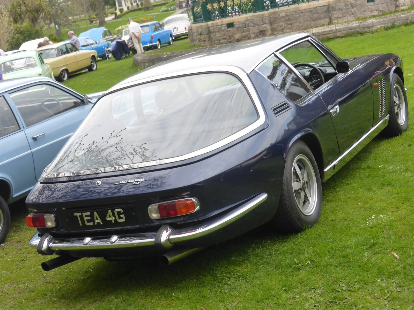 A dark blue Jensen FF seen from the side and rear, showing the front wing vents