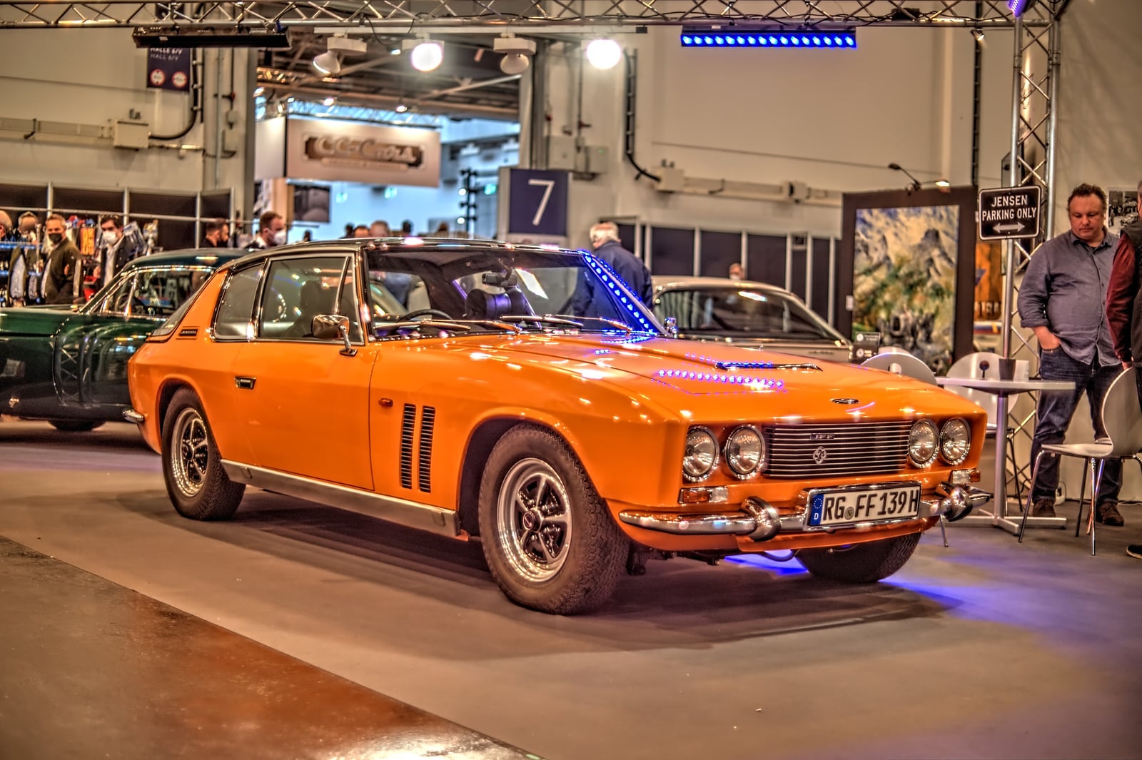 An orange Jensen FF under show lighting, front three-quarter view