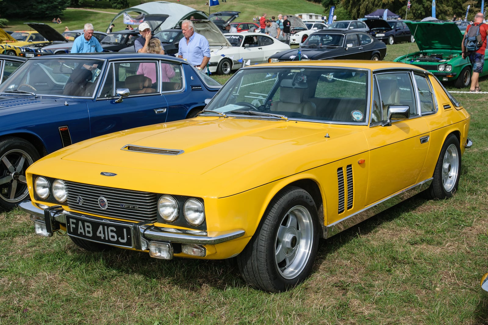 A yellow Jensen FF at a show, front three-quarter view