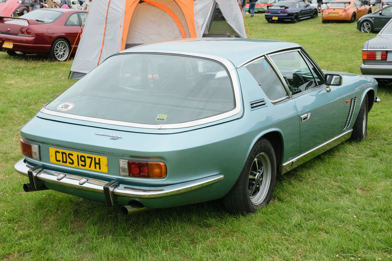 A sage green Jensen FF Mk II seen from the rear three-quarter on grass