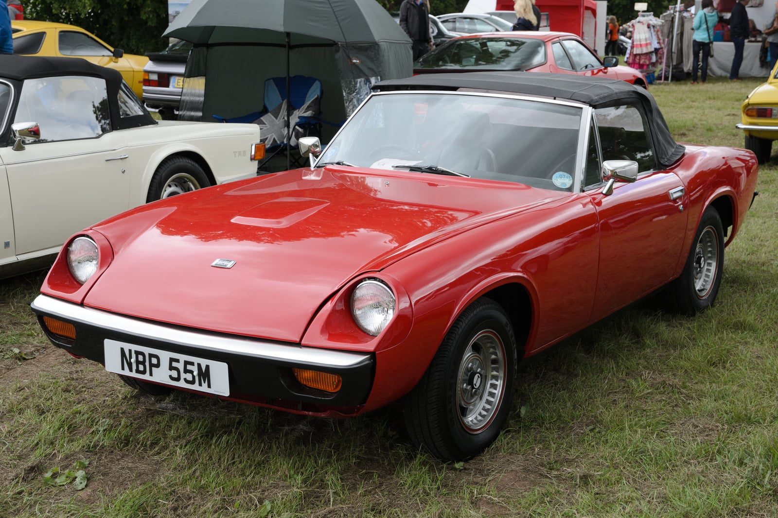 A red Jensen-Healey roadster with the top down at a show, front three-quarter view