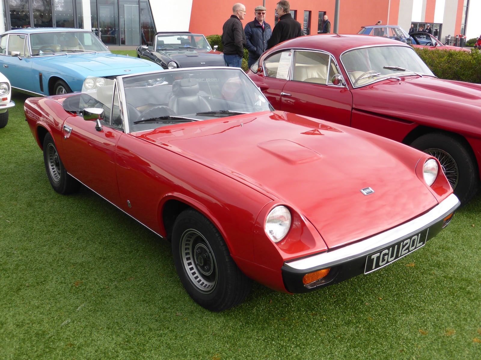 A red Jensen-Healey roadster on a road, front view