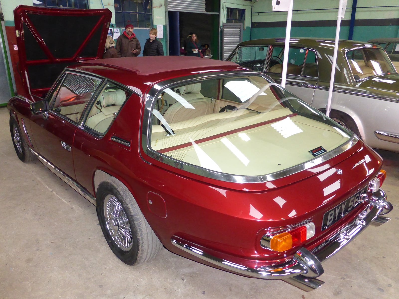 A maroon Jensen Interceptor seen from the rear three-quarter, showing the wraparound glass tailgate