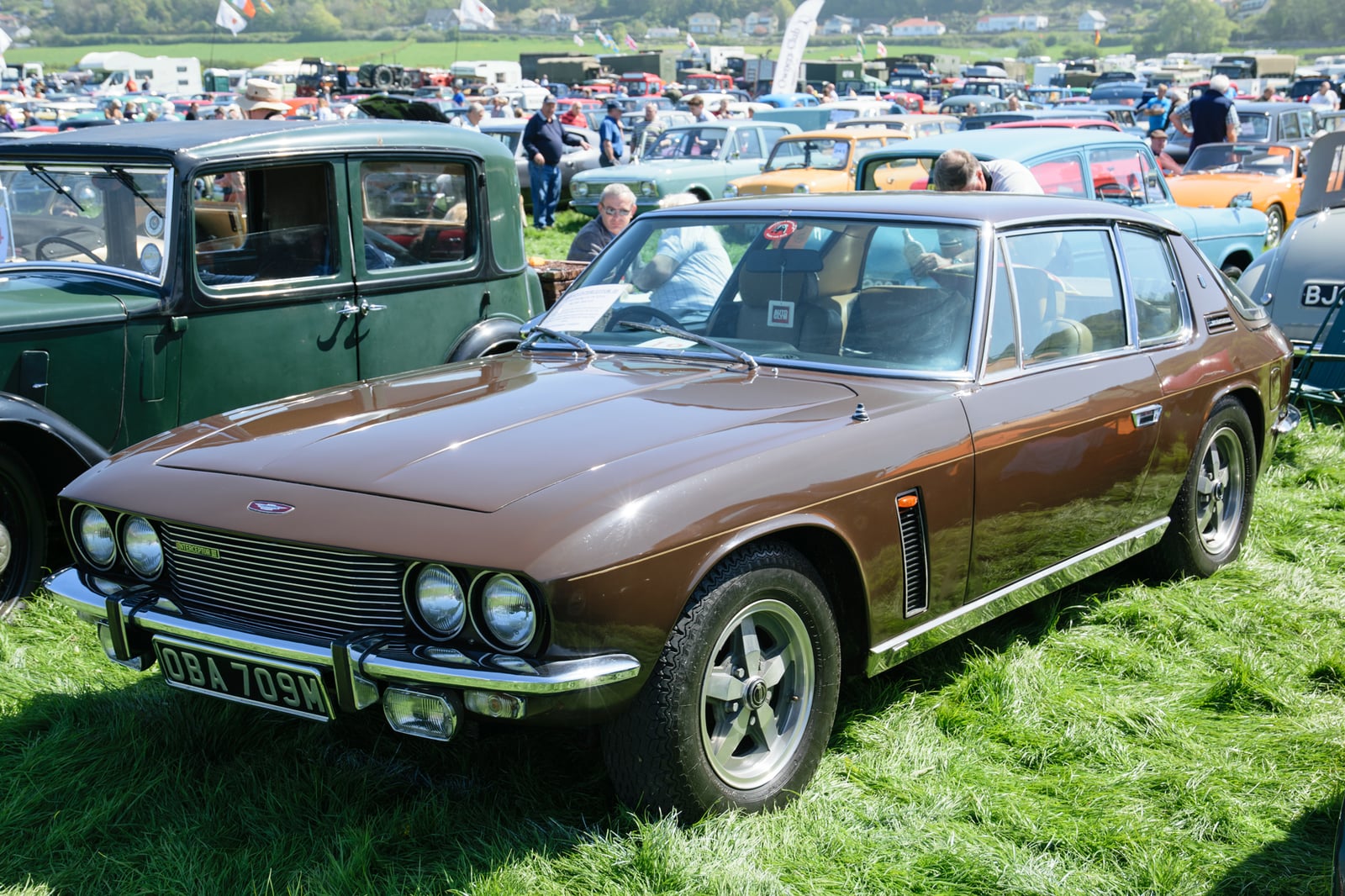A dark red Jensen Interceptor III on grass at a show, front three-quarter view