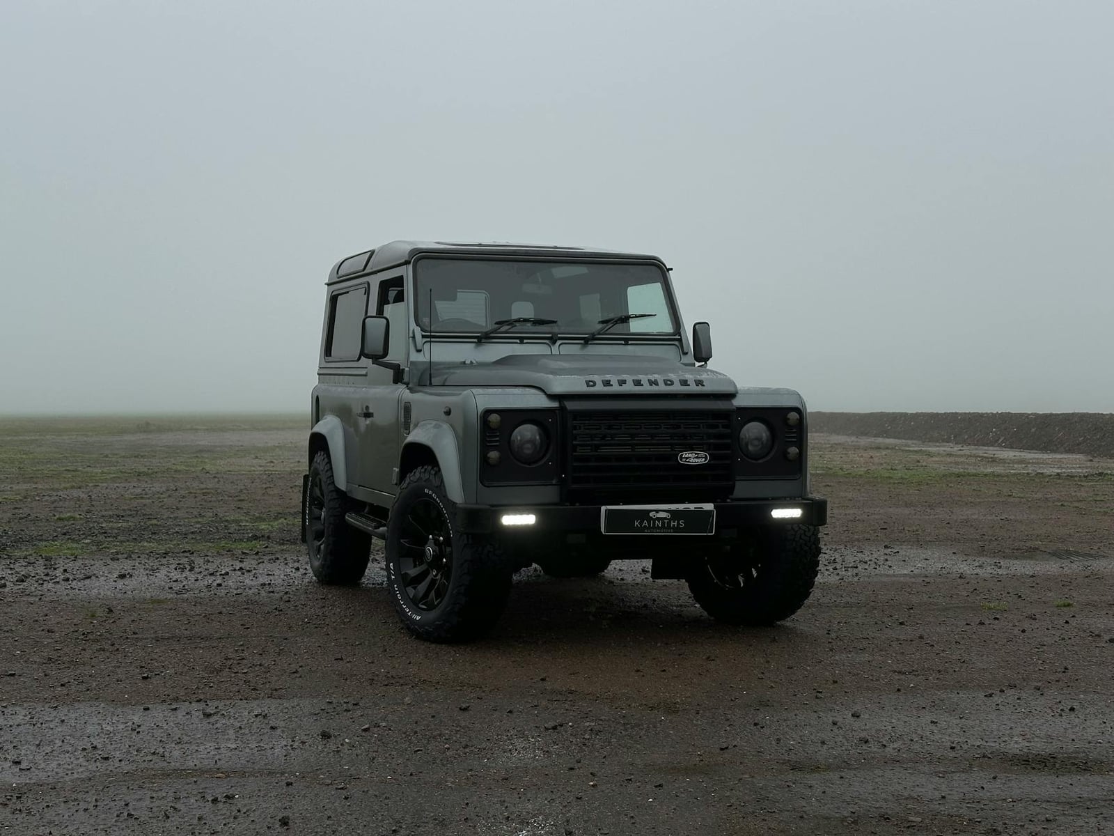 A grey Land Rover Defender 90 parked in fog