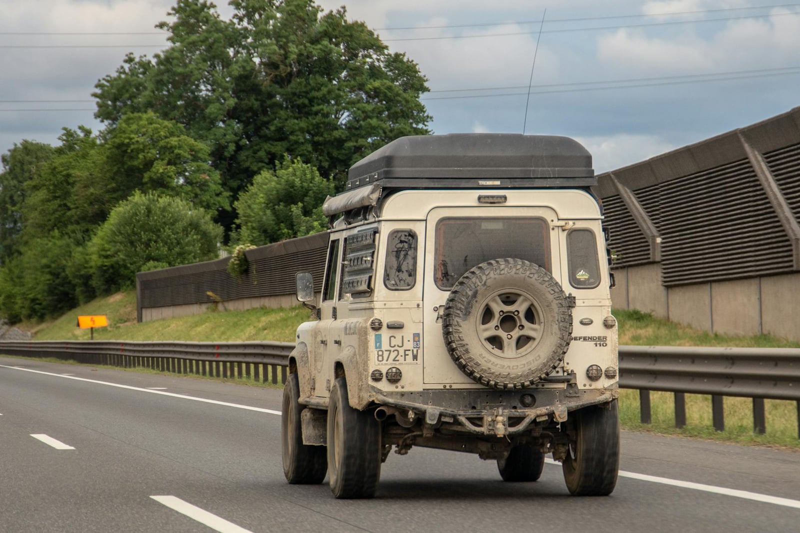 A green and white Land Rover Defender parked kerbside